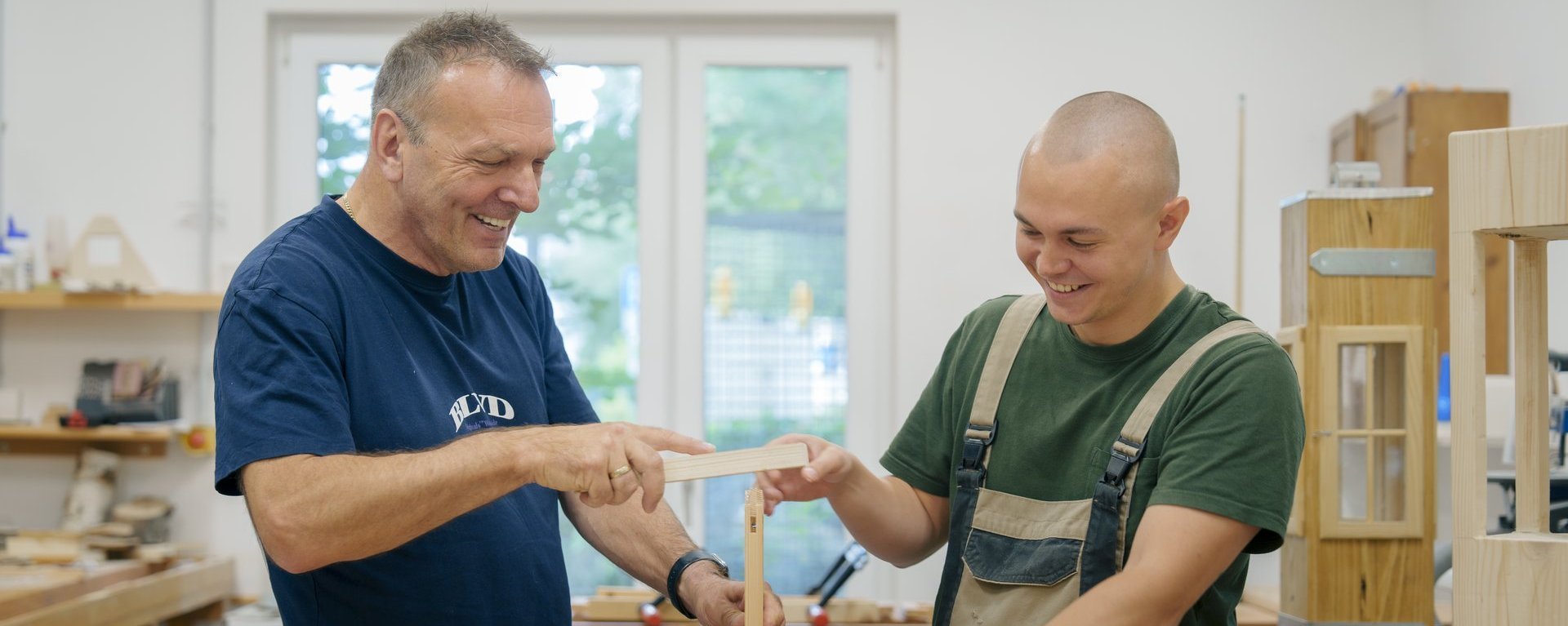 Zwei Männer arbeiten zusammen in einer Werkstatt und haben Spaß 