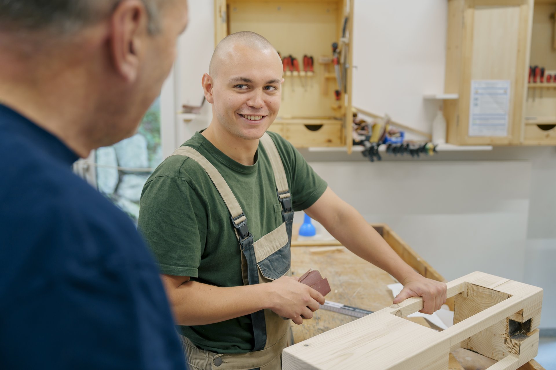 Zwei Männer arbeiten zusammen in einer Werkstatt und haben Spaß 